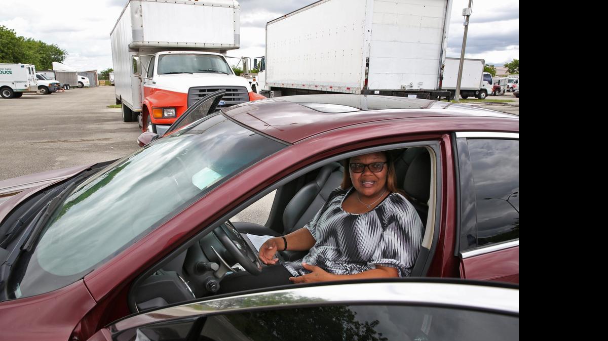 
On the block: Miami-Dade Police spokeswoman Robin Pinkard sits in a 2011 Nissan Maxima, one of the vehicles that was auctioned by the department on June 3. The box truck seen behind the Maxima (used U-Haul truck) was also auctioned.
