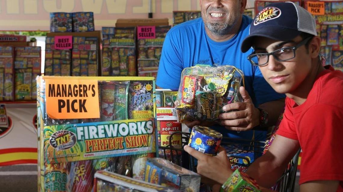 Armando Noche, 47, left, operates “TNT Fireworks” with help from his son Jose, 15, right. Customers are beginning to trickle in to buy fireworks for July Fourth celebration.