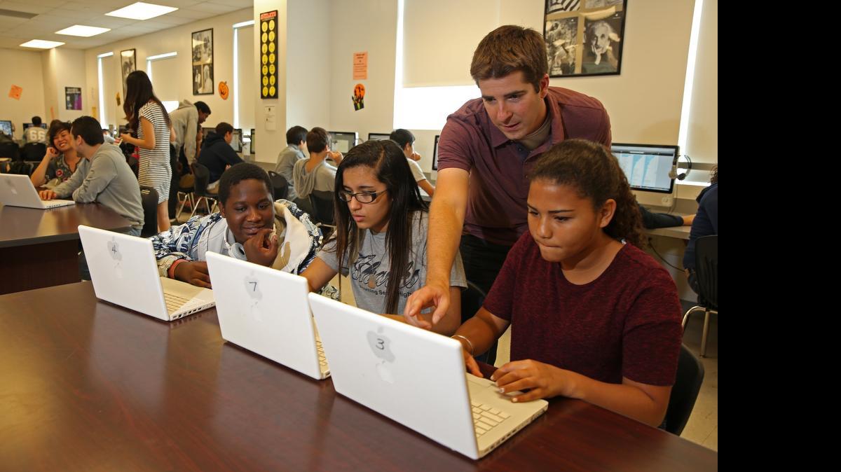 
In the computer lab of Alonzo and Tracy Mourning Senior High School last year, Aaron Levin, an associate product marketing manager, helped train students, from left, Shon Hermilus, Salma El-Jurf and Corina Daniels on using the website LinkedIn. Schools are working to teach kids “digital literacy” skills that extend far beyond the social media that many are already experts in. 
