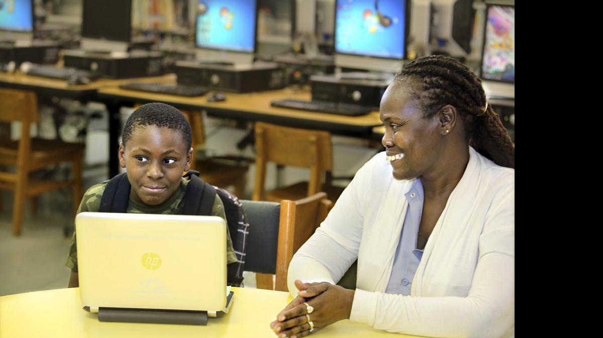 
In the media center at Liberty City Elementary School, Christian Fussell, 11, a rising fifth-grader, and his grandmother Phyllis Richburg talk about how Christian benefited from having the school-issued laptop at home last school year. 
