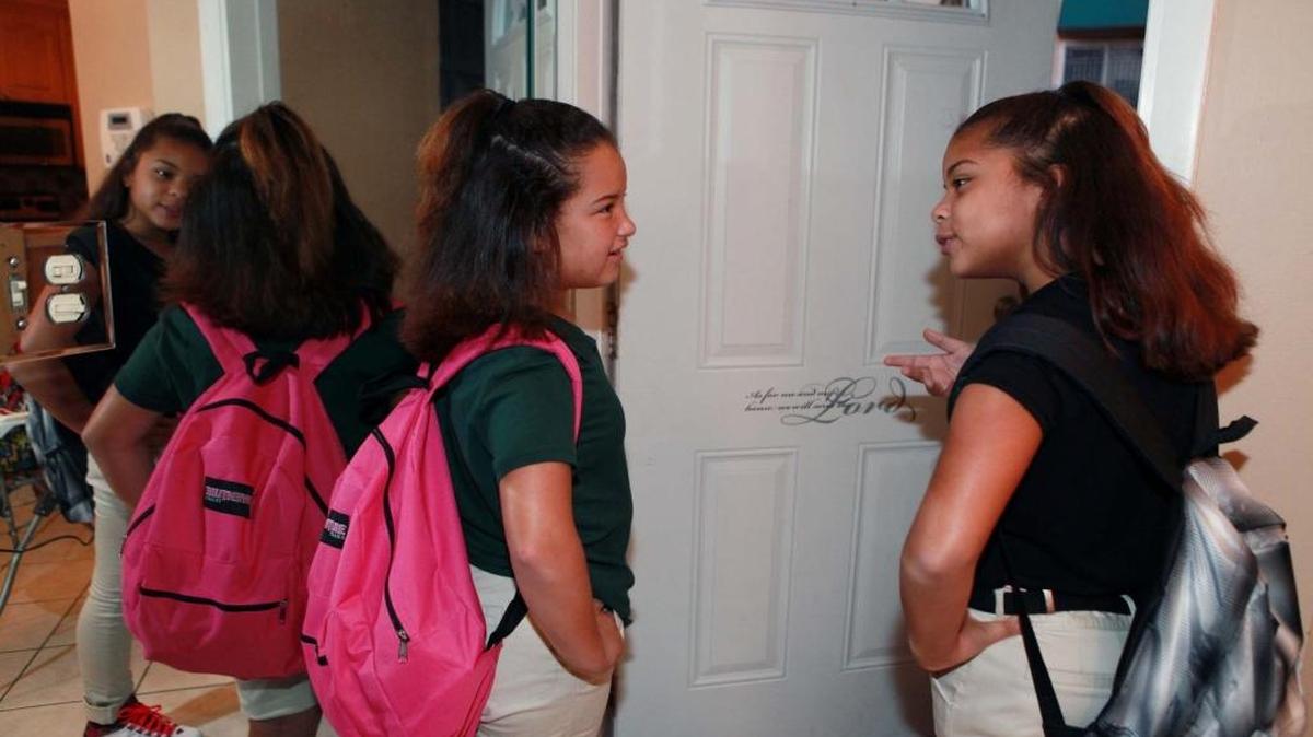 Daisy Martinez, 10, left, and Sara Dominguez, 11, two of Lori Hill’s six foster children, wait to go to school with new backpacks filled with school supplies on the first day of class, Monday, Aug. 22, 2016.