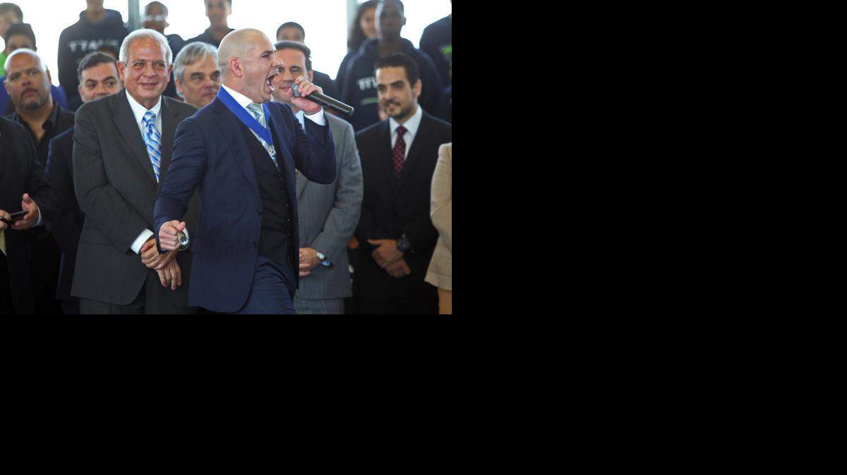 
Rapper Pitbull pumps up the crowd at the Sports Leadership and Management Academy in Little Havana as officials, including Miami Mayor Tomás Regalado, look on.

