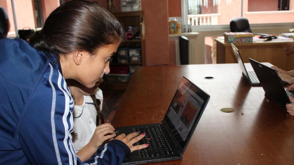 Lourdes ‘Lulu’ de la Peña teaches an elementary school girl how to create her own game using Scratch, a programming language.