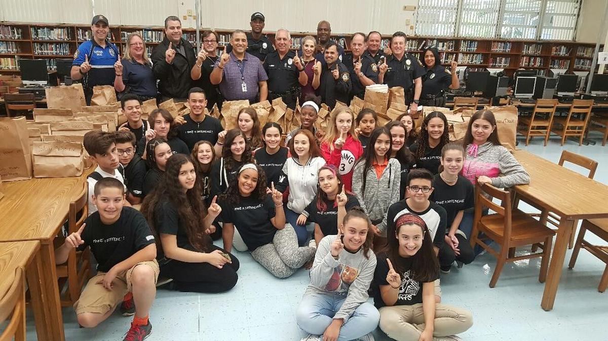 The South Miami Police Department and South Miami Middle School students from the The Power of One club pose with donated blankets at the school’s media center.