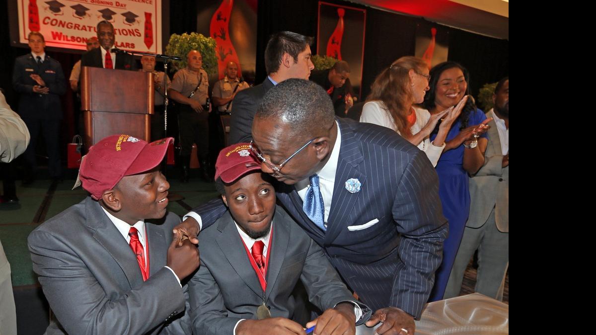 
Larry Handfield, right, shakes hands with Darquavise Dixon, 18, and Deavon Gooden, 18, as they sign for their scholarships to Bethune-Cookman University during the Academic Signing Day ceremony. Eighty-four graduating seniors signed scholarships to the colleges and universities of their choice at the 5000 Role Models of Excellence's ceremony on Monday, June 8, 2015.

