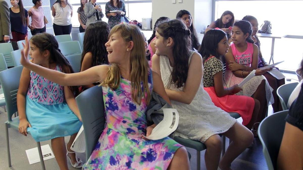 
Kara Oliveira, left, and Tamara Navarre, 10, both look back as Kara waves to their computer mentor as she entered back of the room at the Idea Center at Miami Dade College Wolfson Campus.
