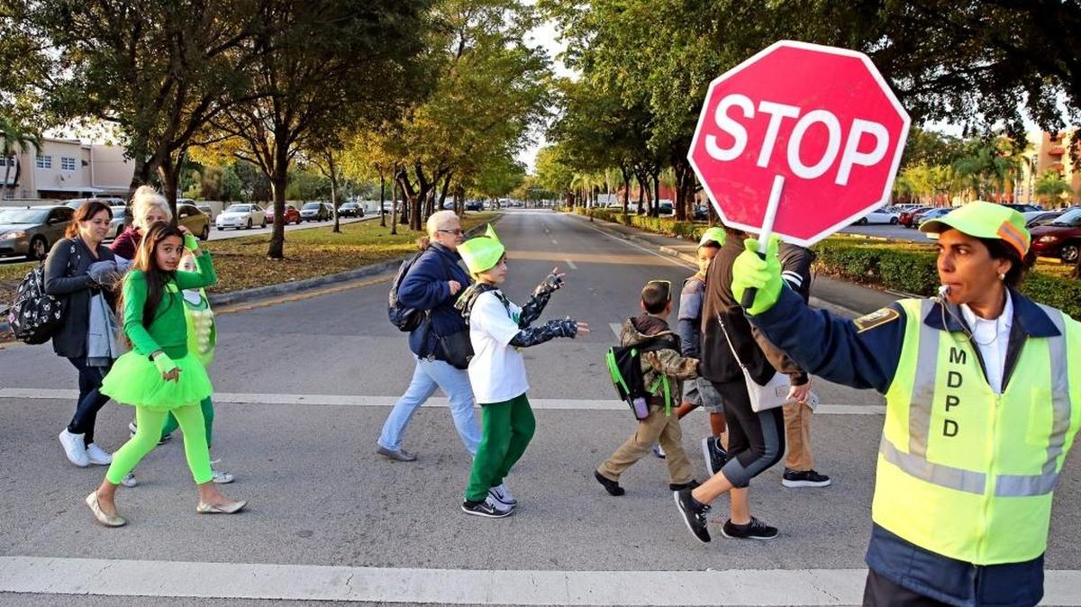 A crossing guard stops traffic as Wesley Matthews Elementary students cross Southwest 122nd Avenue.