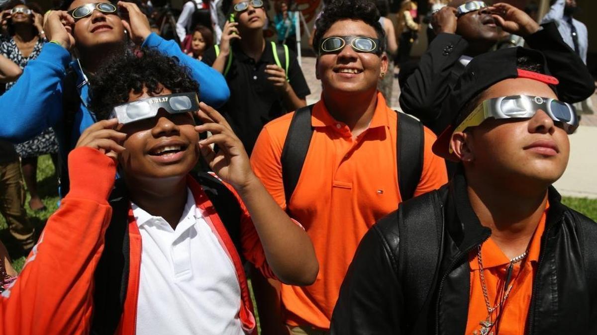 On the first day of school, students, teachers, and faculty members gaze toward the sky to witness the partial eclipse at Booker T. Washington Senior High School on Monday, August 21, 2017.