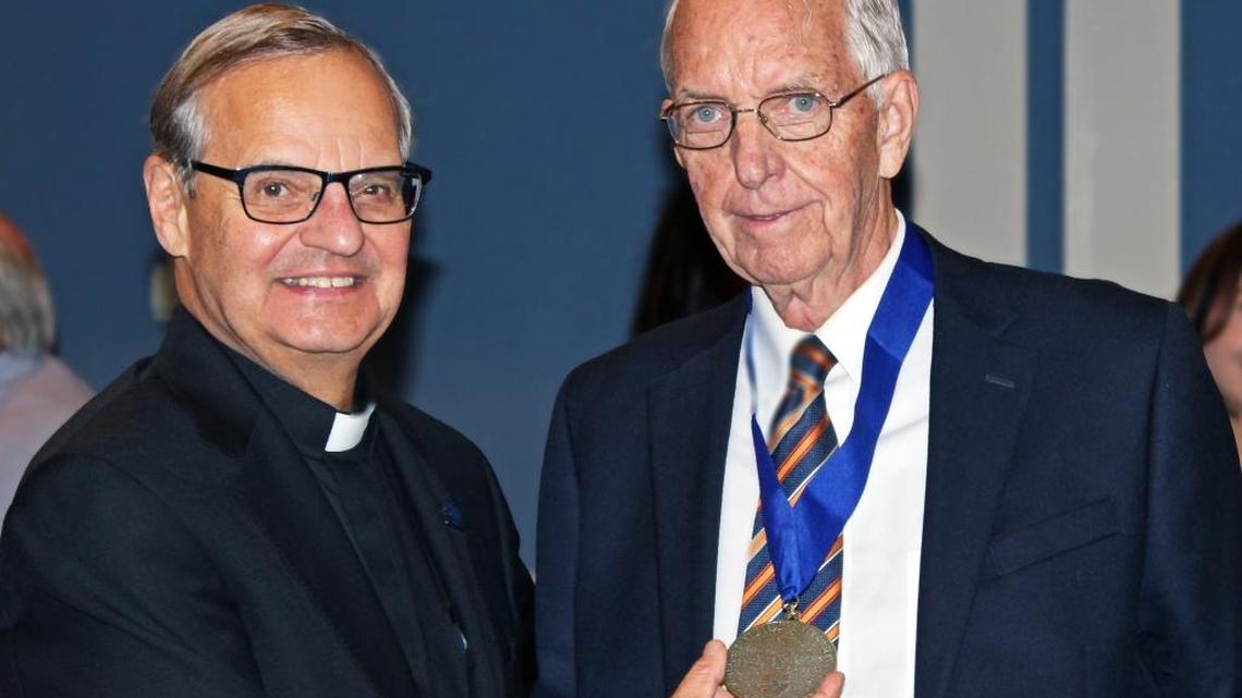 St. Thomas University Professor Richard Raleigh, right, and school President the Rev. Msgr. Franklyn Casale show Raleigh's Presidential Award for Distinguished Service.