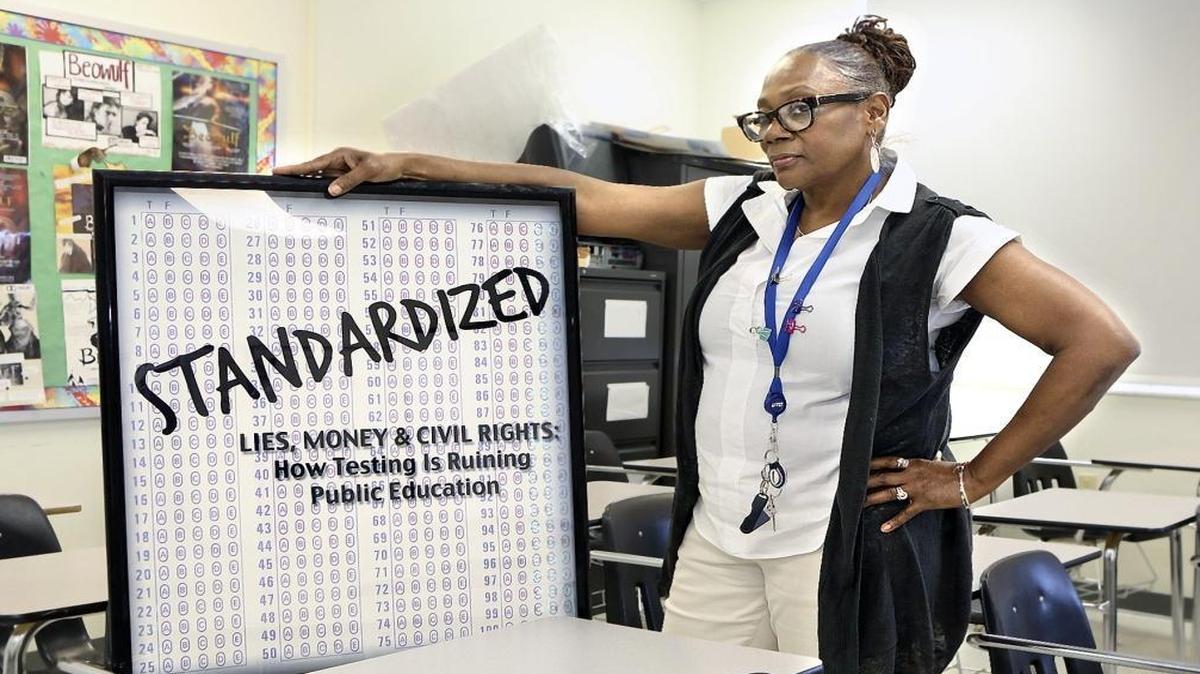 Ceresta Smith poses with a movie bill for "Standardized," a 2013 documentary about the adverse effects of standardized testing, on Thursday, April 21, 2016 in her classroom at John A. Ferguson Senior High School. Smith teaches English to seniors and is a co-founder and administrator of United Opt Out National.