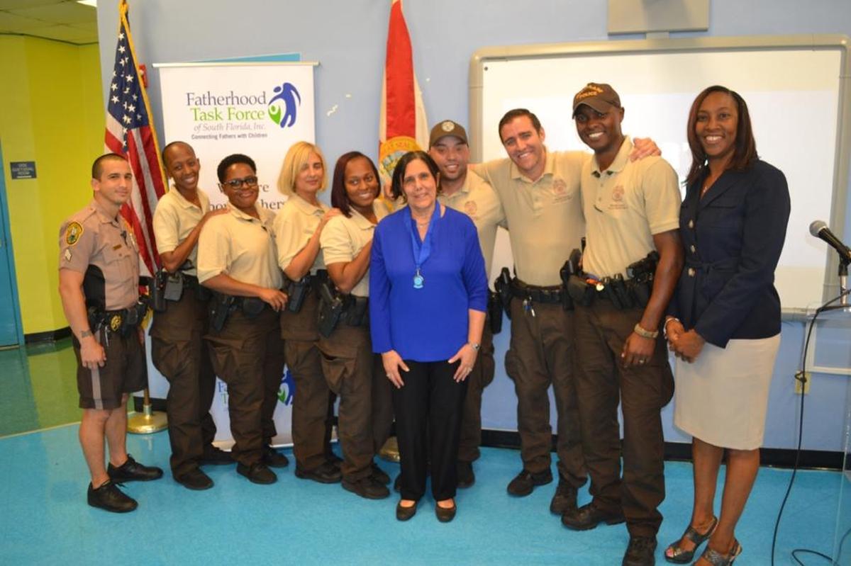 Officer Edward Wade, right, of the Miami-Dade County Police Department stands with his squad, Principal Carol Sampson, far right, and Holly Zwerling, center, during the Fatherhood Taskforce's Father's in Education Day breakfast.