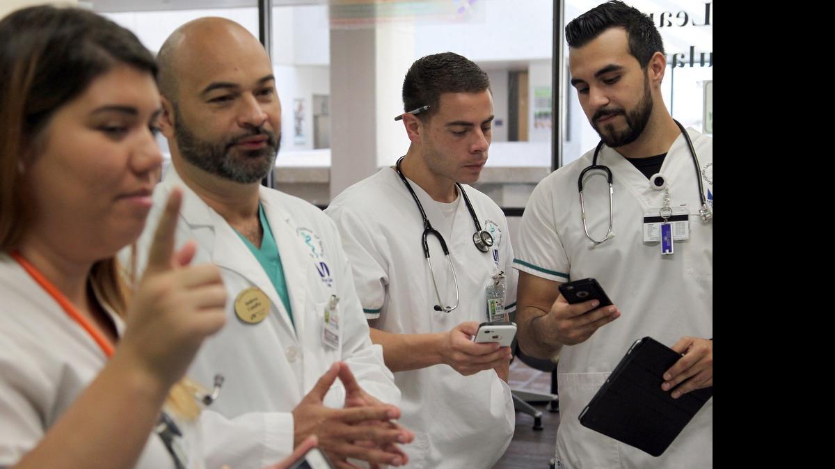 
Andres Caiaffa, a professor at Miami Dade College’s Benjamin Leon School of Medicine, allows students to use tablets and smartphones as part of the classroom experience at the Simulation Lab. From left, Cassandra Gonzalez, Andres Caiaffa, Alex Escoto and Enrique Gil.
