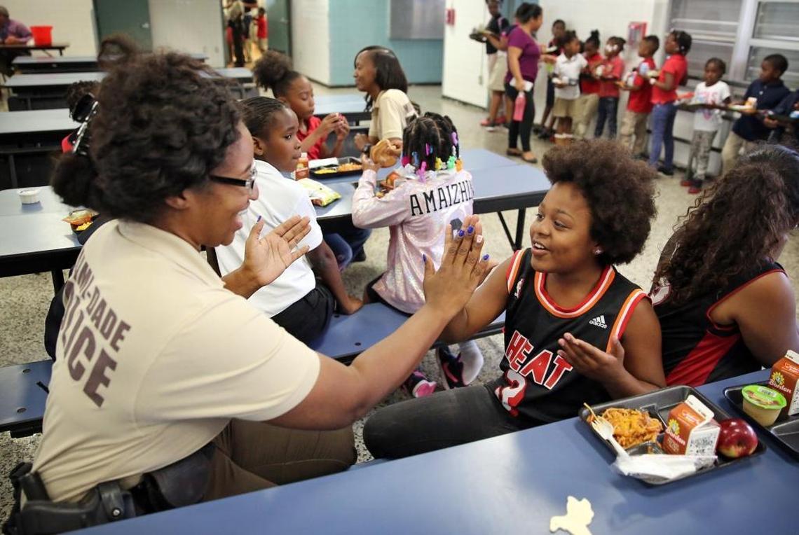 Miami-Dade police officer Camille Normil, plays a game of numbers patty-cake with third-grader Jayla Scott, 9, during lunchtime at Poinciana Park Elementary School, Tuesday morning, May 16, 2017. The two have become fast friends since the Miami-Dade Police Department started sending its officers to the school to have lunch with students.