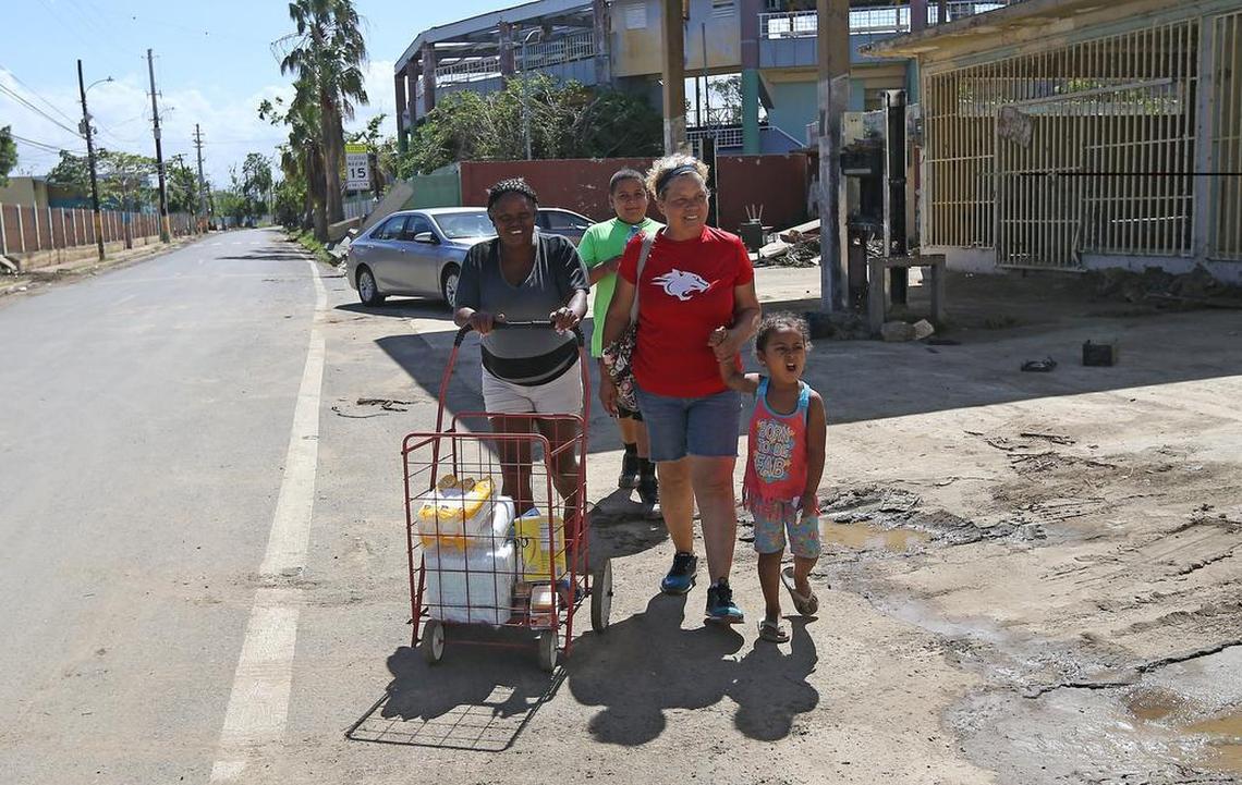 Toa Baja resident Lourdes Ayala, with Carmen Santiago and her grandchildren, Yomar Santiago and Johalyz de la Cruz, walk with aid for people in need in the aftermath of Hurricane Maria in Puerto Rico on Tuesday, October 24, 2017.