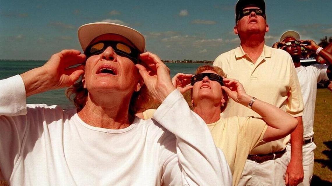 Ellie Nydick of New York City, Anne and Mike Barrett of Hazlet, New Jersey and Anthony Williams of Miami all watch the solar eclipse at Key Biscayne on February 26, 1998.