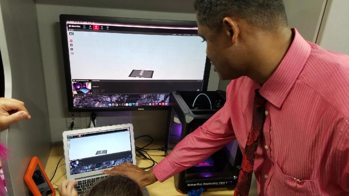 Marlon Moore teaches 7-year-old Maria Teresa Lombardi how to use a 3D printer aboard Miami-Dade Library’s new Technobus.