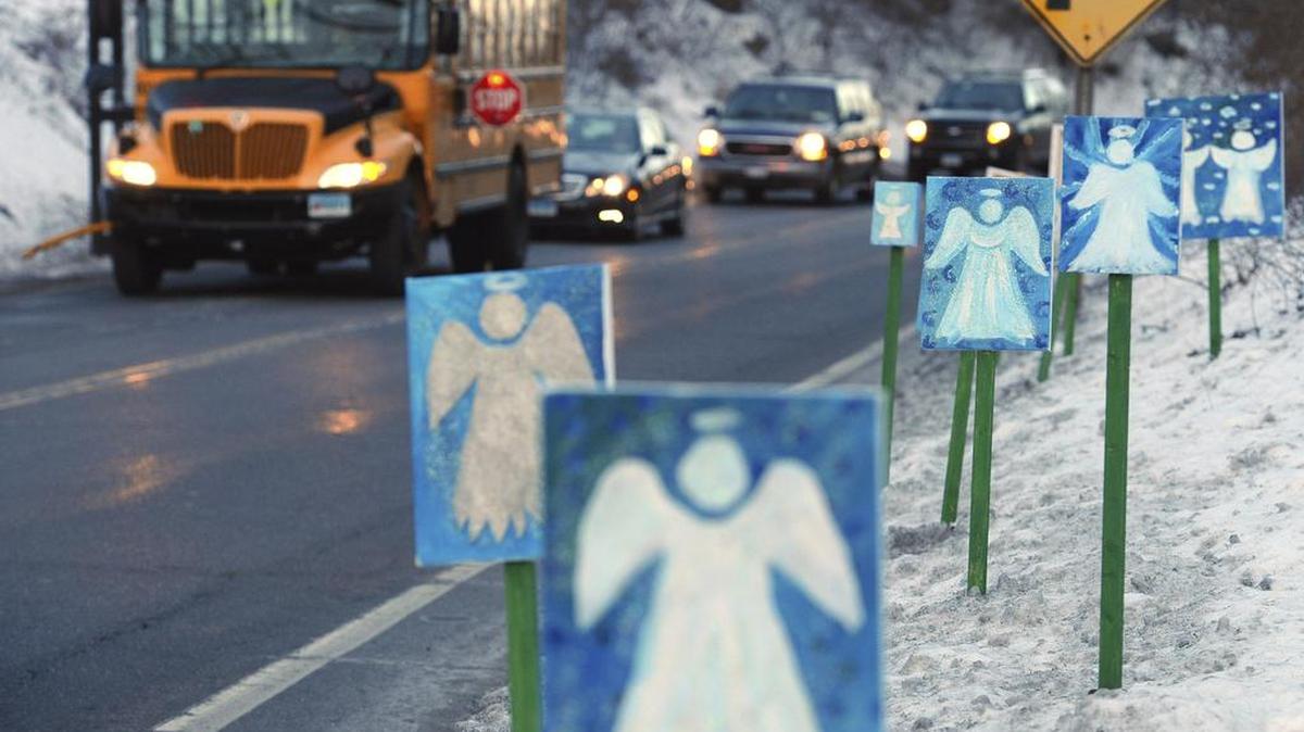 In this Jan. 3, 2013, file photo, a bus traveling from Newtown, Conn., to Monroe stops near 26 angel signs posted along the roadside in Monroe, Conn., on the first day of classes for Sandy Hook Elementary School students since the Dec. 14, 2012, shooting.