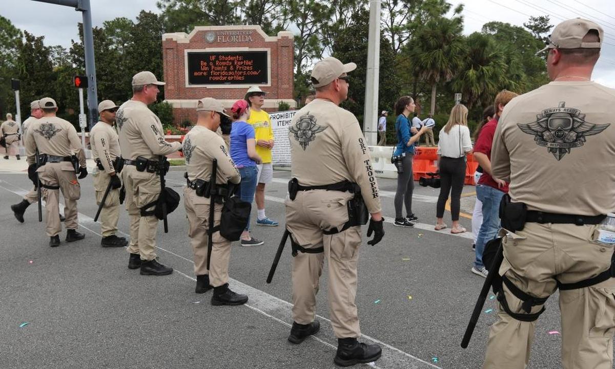 Florida Highway Patrol troopers stand ready at the entrance to University of Florida in Gainesville as hundreds of protesters march near the Phillips Center, where Richard Spencer was allowed to speak.