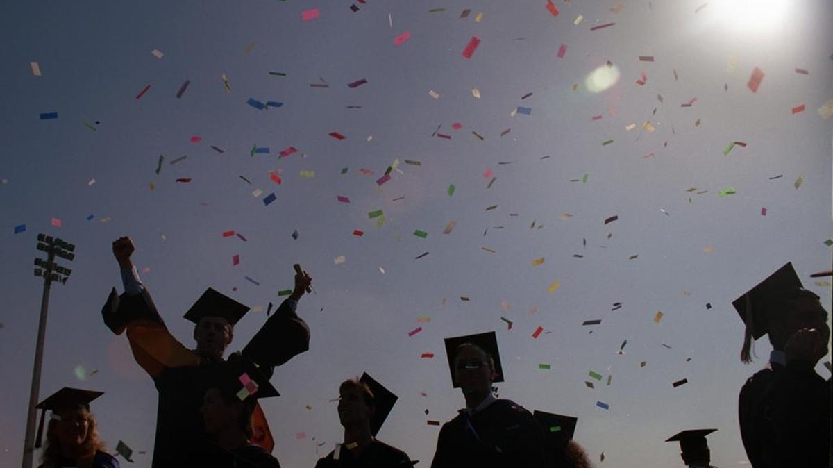 Pieces of confetti litter the sky as graduates celebrate during an FIU commencement ceremony.