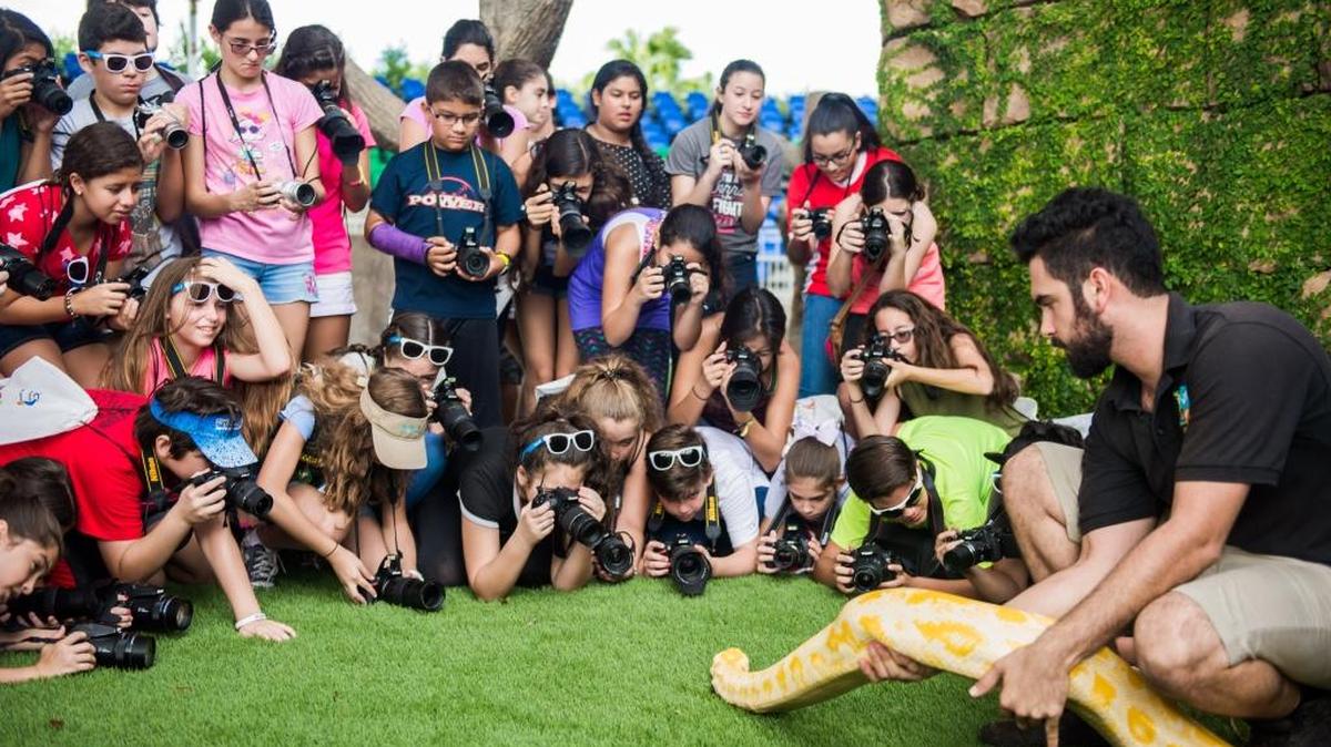 South Florida middle school students taking photos of a Zoo Miami worker with a snake for the Mercantil Commercebank 2016 Zoolens Photography Project.