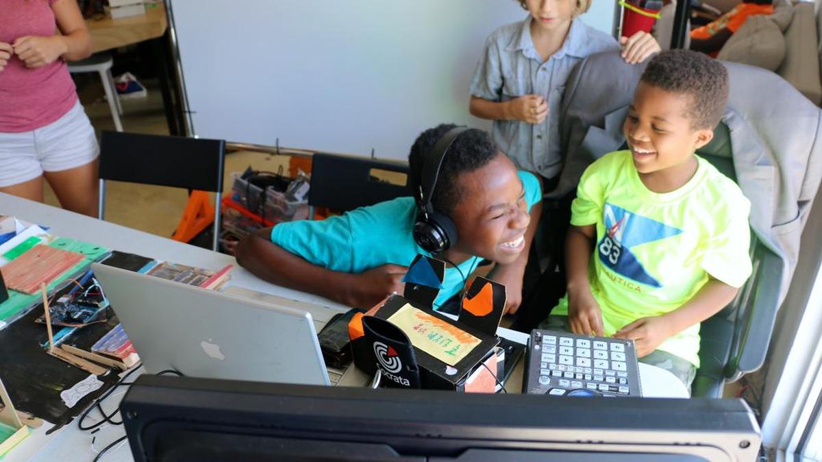 Daniel Randolph, in headphones, and his cousin, A.J. Randolph, enjoy themselves at Wynwood Maker Camp as Kai Prol watches them from behind.