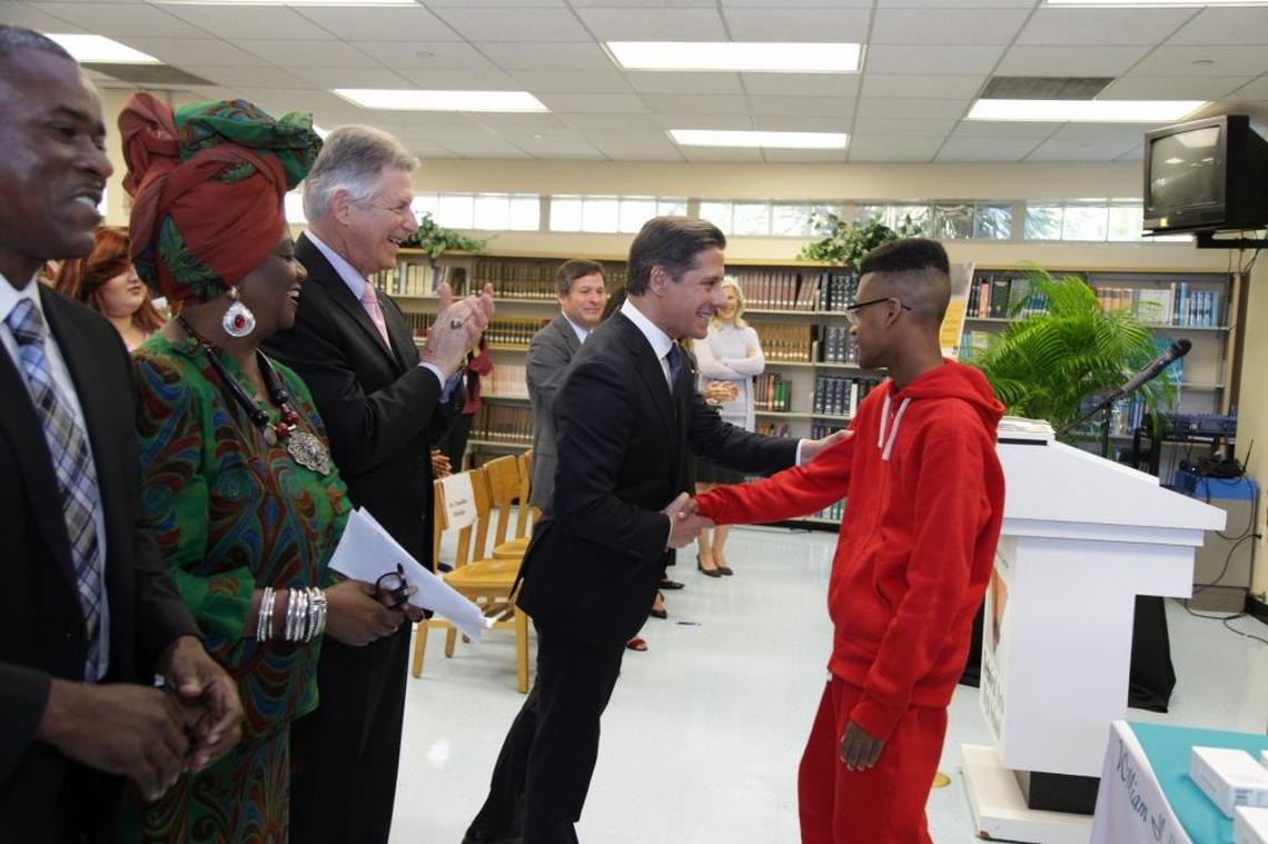 Miami-Dade Public Schools Superintendent Alberto Carvalho (center) shakes hands with William H. Turner Technical Arts High School 10th grader Sadre Campbell.