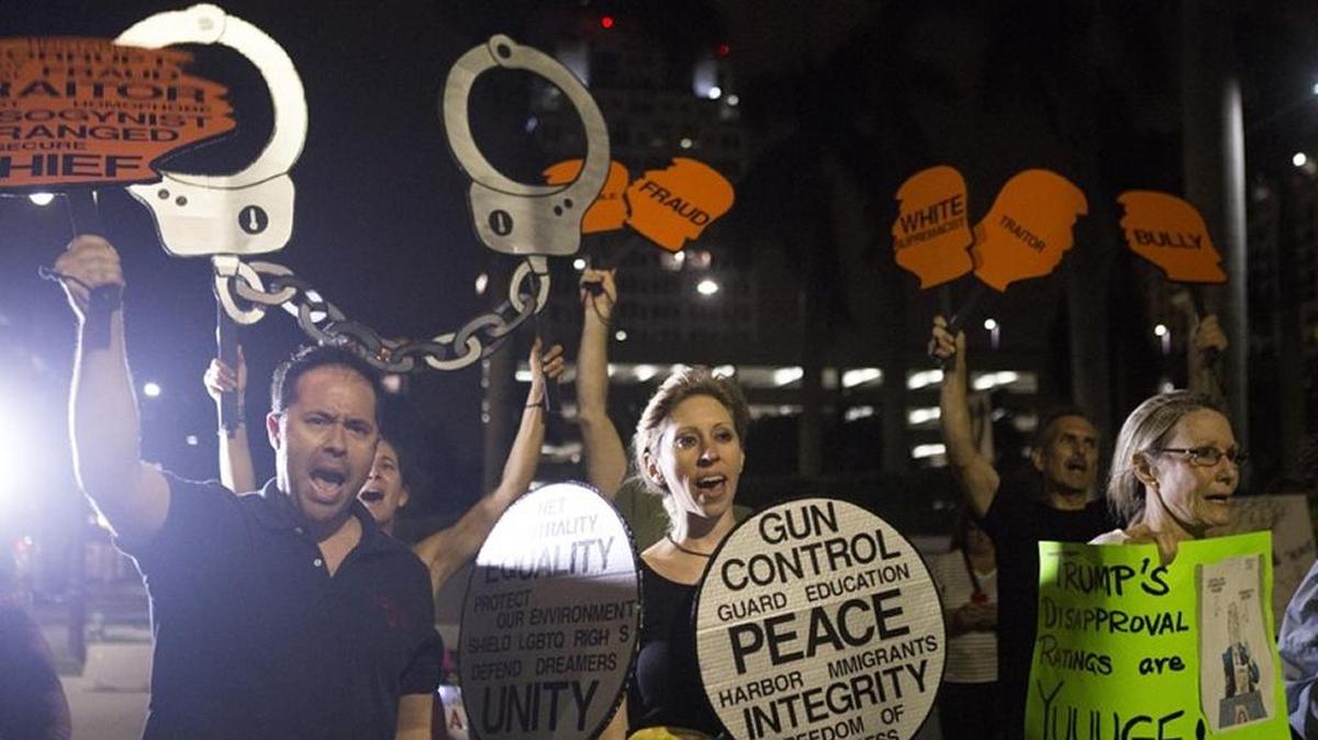 People shout during a demonstration at Trump Plaza on Saturday, Nov. 11, 2017, in West Palm Beach.