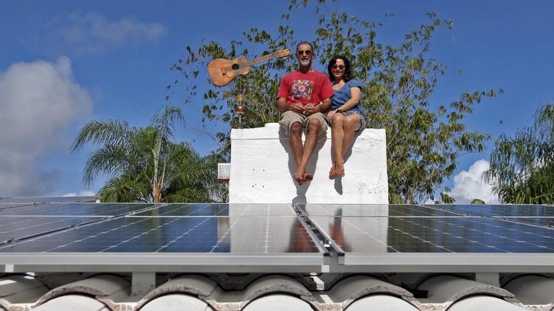 Simon Rose sits on his solar panel covered roof with his girlfriend Jody Finver in his North Coconut Grove neighborhood on Thursday, November 19, 2015.
