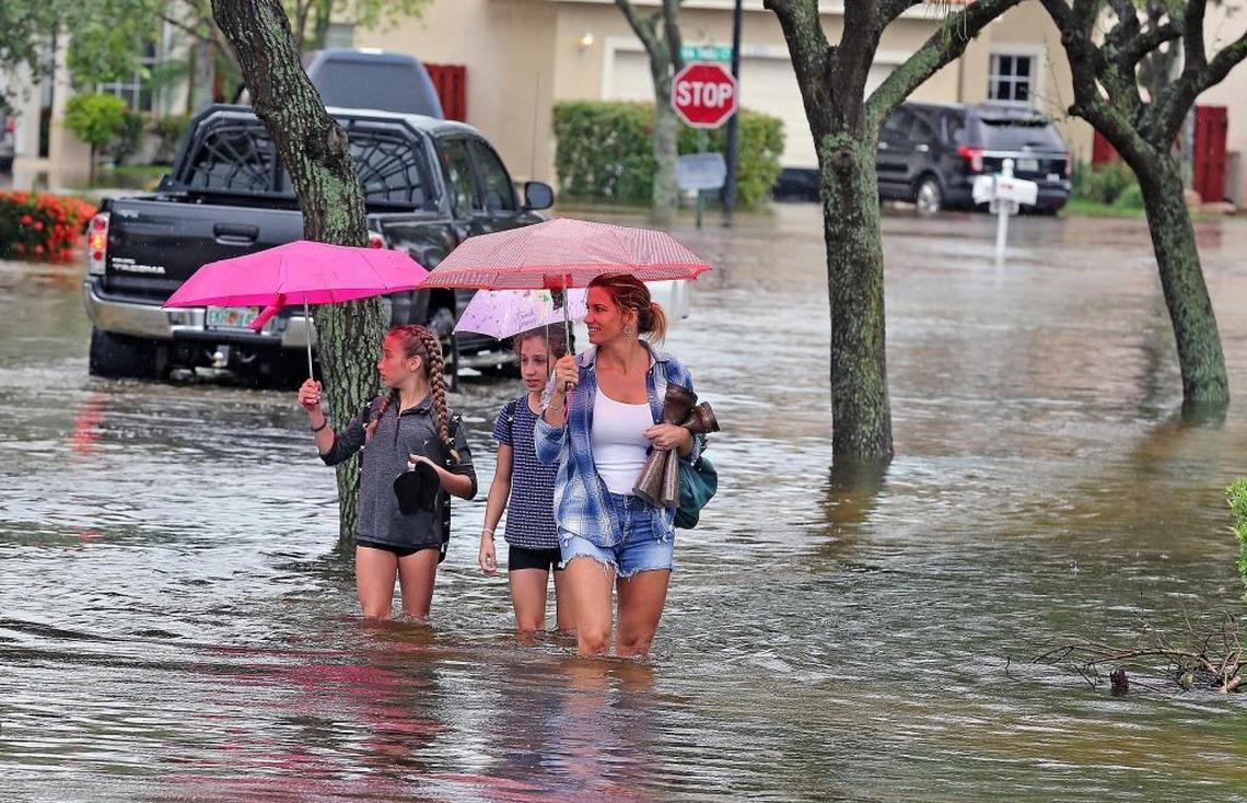 Leah Bonneau walks with her daughter Shanely 12, and her friend Amanda Sanders 12 in the Vista Filare neighborhood in West Davie on Wednesday following record-breaking rain.