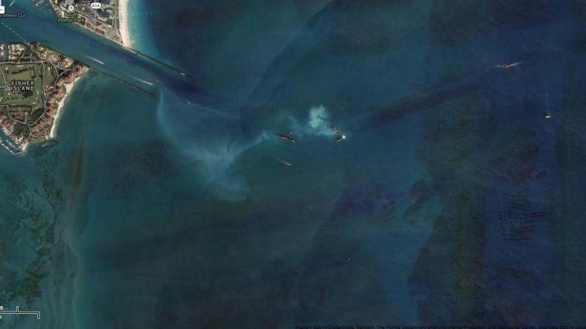 Sediment forms a white plume trailing a barge hauling mud dredge from Government Cut to an offshore disposal site.