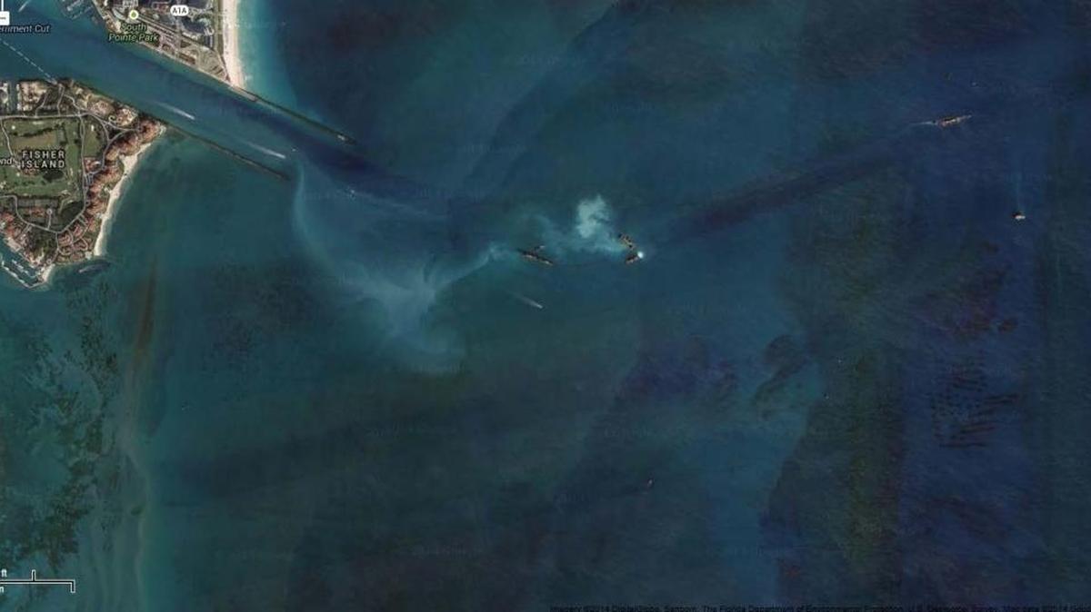 Sediment forms a white plume trailing a barge hauling mud dredge from Government Cut to an offshore disposal site.