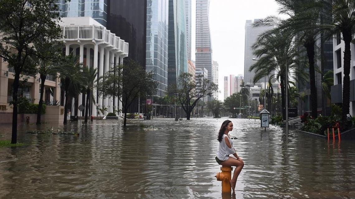 Mia Herman perches atop a fire hydrant after Hurricane Irma flooded Brickell Avenue in September. The National Hurricane Center recently concluded that rainfall and poor drainage caused flooding along parts of the street not adjacent to Biscayne Bay.