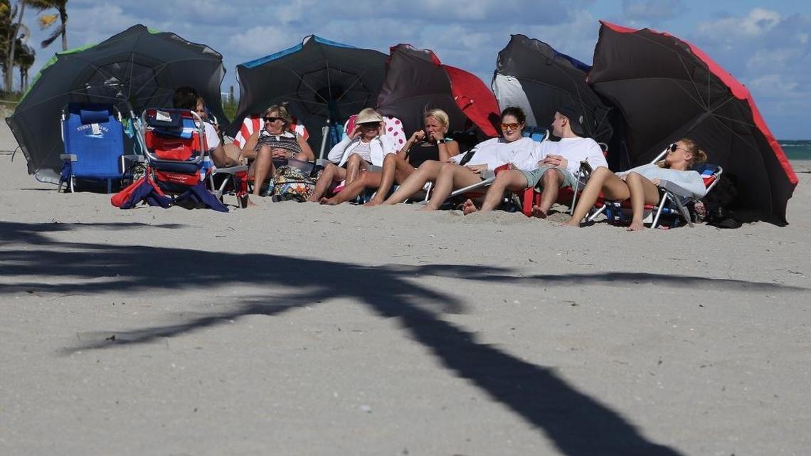 Canadian tourists bask in the sunlight as the rough surf crashed against the shoreline, January 7, 2018.
