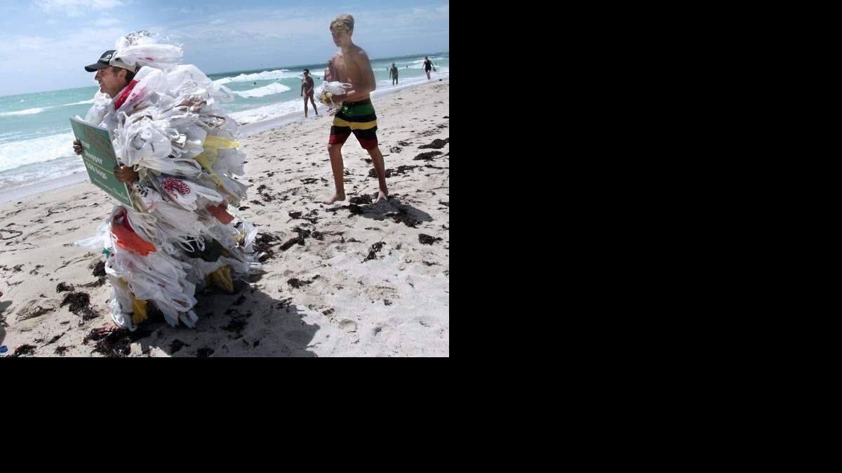 FILE - Steve Vicenti of Miami Beach, left, dressed in a suit of plastic bags to take part in an event on Saturday, May 17, 2014. "I am pushing a reduction of single-use plastics. The average person uses 500 bags in a year," Vicenti said. "They do not degrade. If only we could live as long as the average plastic bag or bottle." 