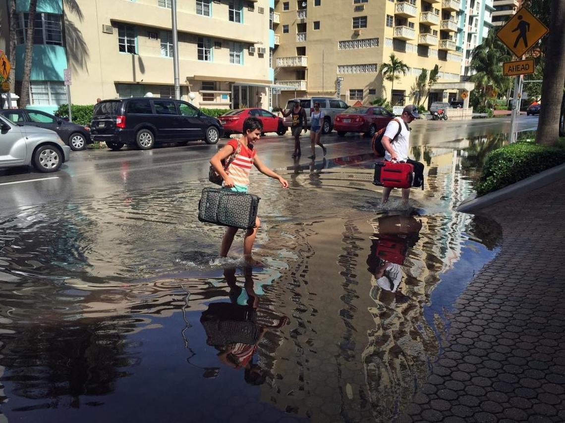 Oakley and Casey Jones, tourists from Idaho Falls, navigate the flooded streets of Miami Beach as they make their way to their hotel on Collins Ave. and 30th Street during a king tide.