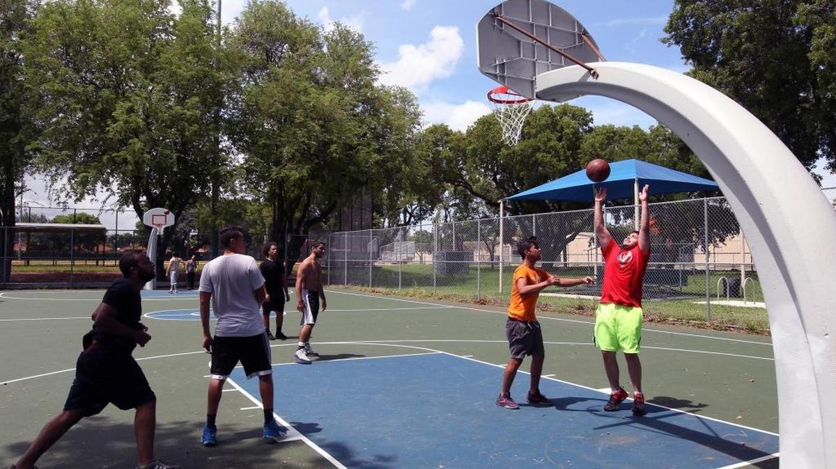 A group of teenagers play basketball at Douglas Park on Thursday, June 29, 2017. Douglas Park, which was closed for three and a half years due to contaminated soil, reopened on Thursday after a cleanup by the City of Miami.