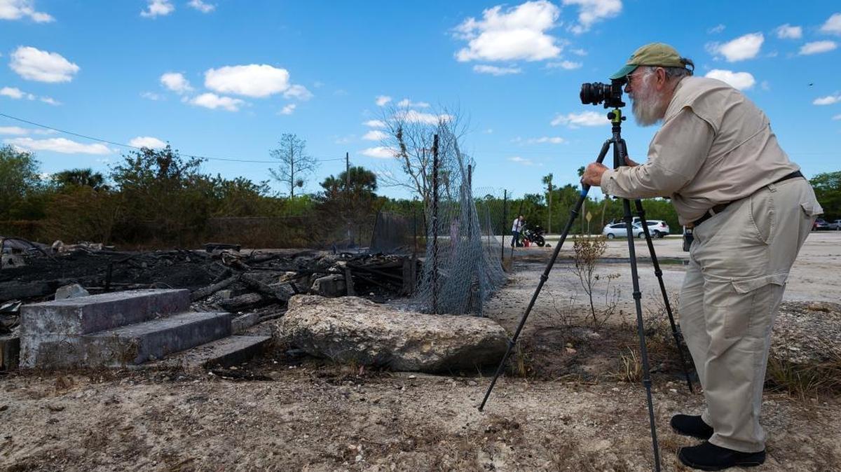 Famed Everglades photographer Clyde Butcher photographs the smoldering ruins of the historic Monroe Station on Sunday after a fire gutted it.