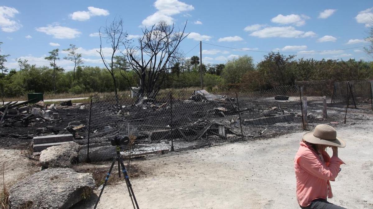 In a Sunday, April 10, 2016 photo, Niki Butcher takes a break while photographing the aftermath of a fire that destroyed the landmark Monroe Station in Ochopee earlier this year. Monroe Station was on the U.S. National Register of Historic Places and was originally constructed in the 1920s.