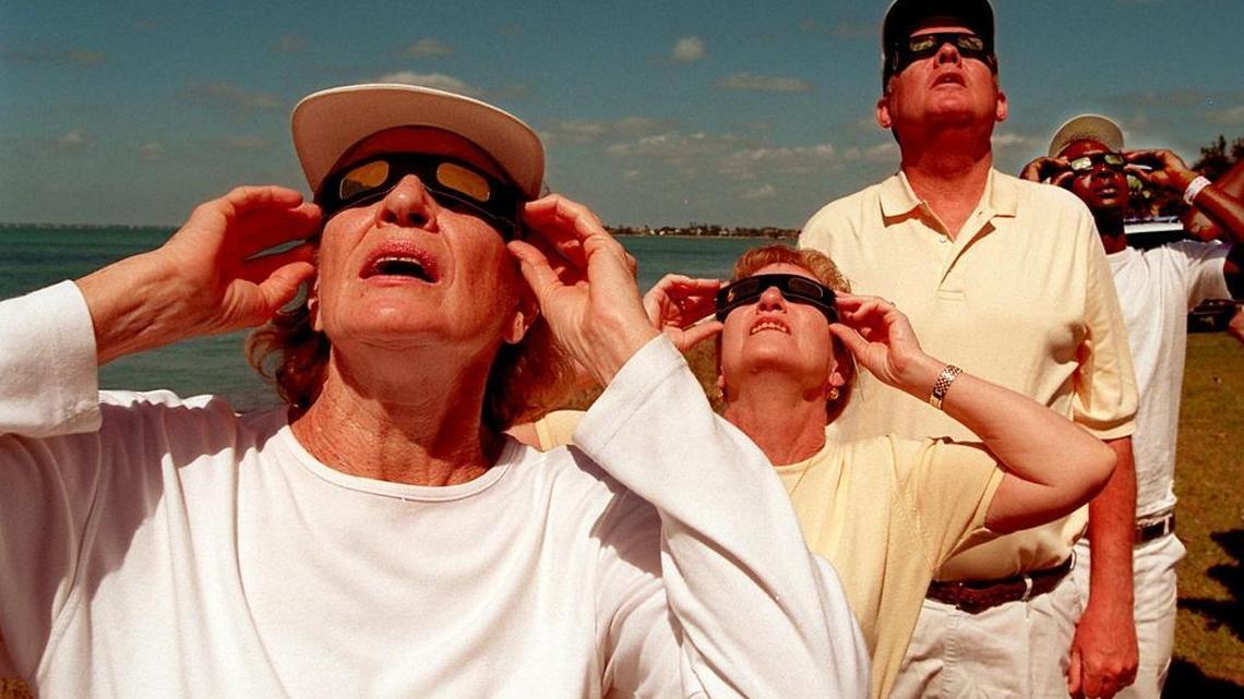 Ellie Nydick of New York City, Anne and Mike Barrett of Hazlet, New Jersey and Anthony Williams of Miami all watch the solar eclipse at Key Biscayne on February 26, 1998. Although those in South Florida will only see a 72 percent eclipse this year — the path sprawls from Salem, Oregon to Charleston, South Carolina — looking into the partial eclipse can still be dangerous to the naked eye.