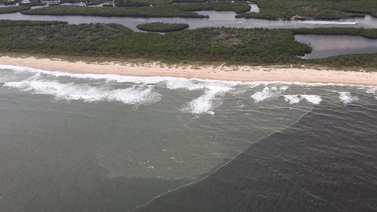 A line of black water moves out of the St. Lucie Inlet south along the coast.
