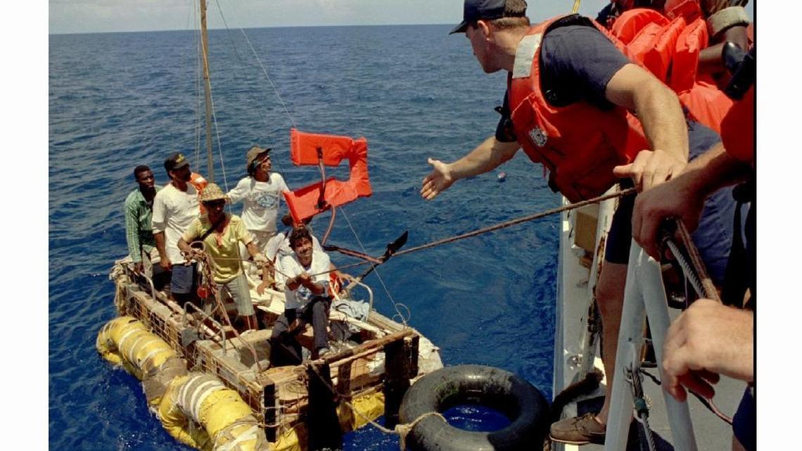 Dave Brede of the U.S. Coast Guard tosses Cuban rafters life jackets as they pull along side of the makeshift raft Sept. 5, 1994, in the Florida Straits. New U.S. policy ends so-called ‘wet-foot, dry-foot’ admission.