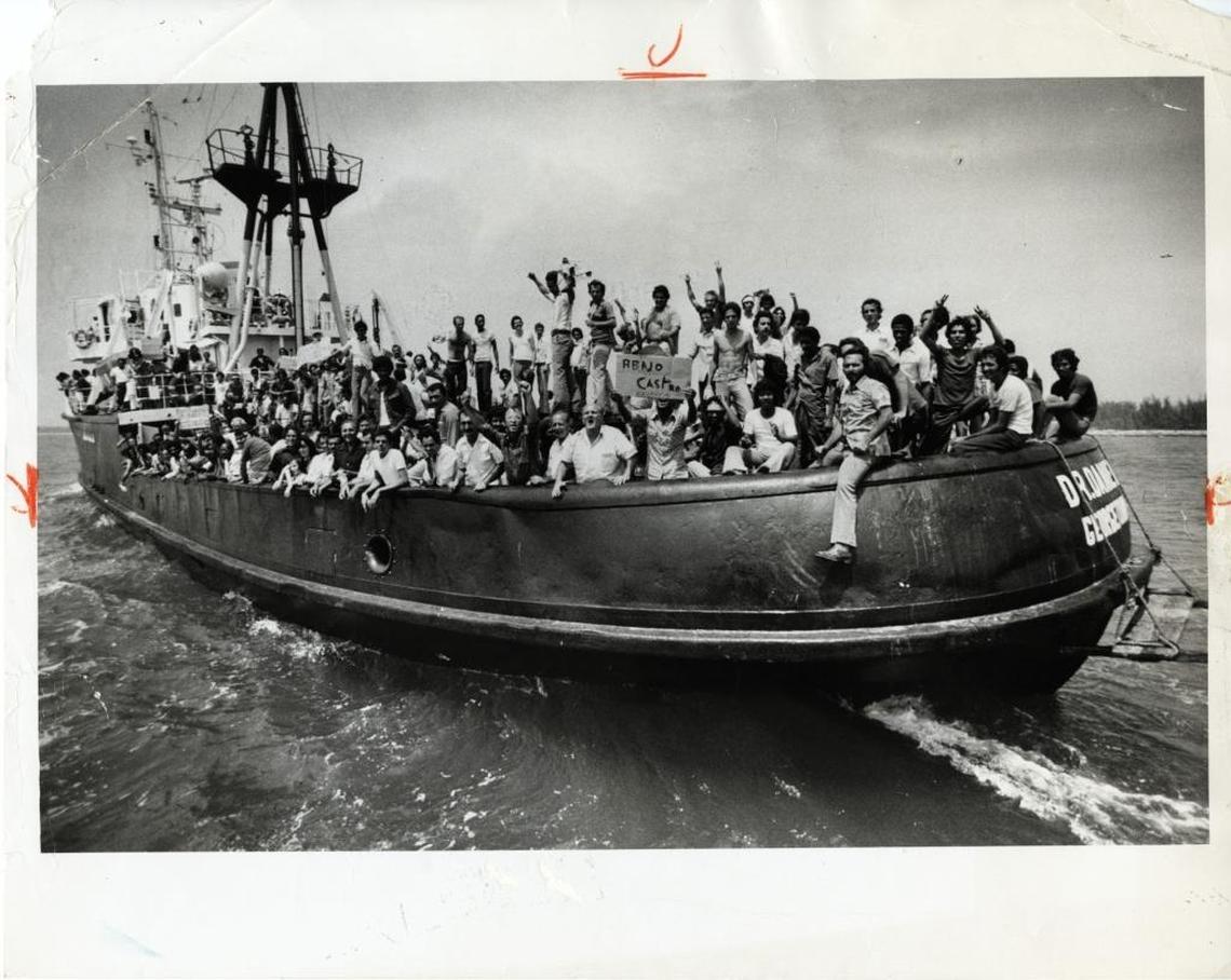 The Dr. Daniels, loaded with 600 to 700 Cuban refugees, pulls into the docks at Key West; one refugee aboard holds up a sign in Spanish that says "Down With Castro." Ran with story "U.S. to help with refugees" that leads with "President Carter declared a state of emergency in those parts of Florida 'severely affected' by the wave of Cuban refugees arriving in the Mariel-to-Key West sealift."