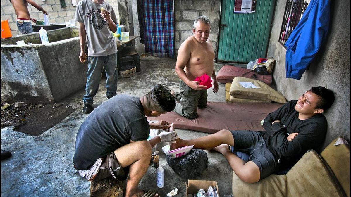Activist Irineo Mujica Arzate works on a young man’s blistered feet at the Centro de Ayuda Humanitaria, Center for Humanitarian Aid, in Chahuites, Mexico.