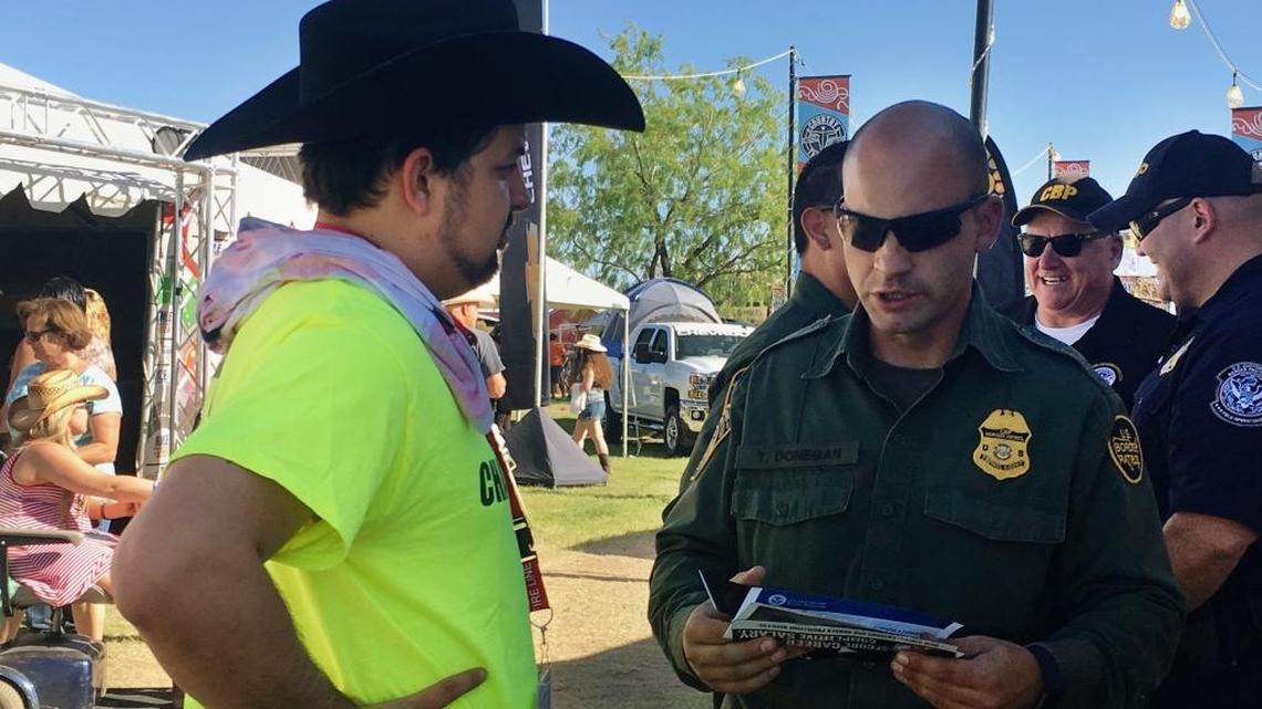 In this April 6, 2017 photo, a U.S. Border Patrol agent gives information about working for the agency to 24-year-old Ric Kindle, of the Phoenix area, at the Country Thunder Music Festival in Florence, Ariz. President Donald Trump has ordered 5,000 new Border Patrol positions.