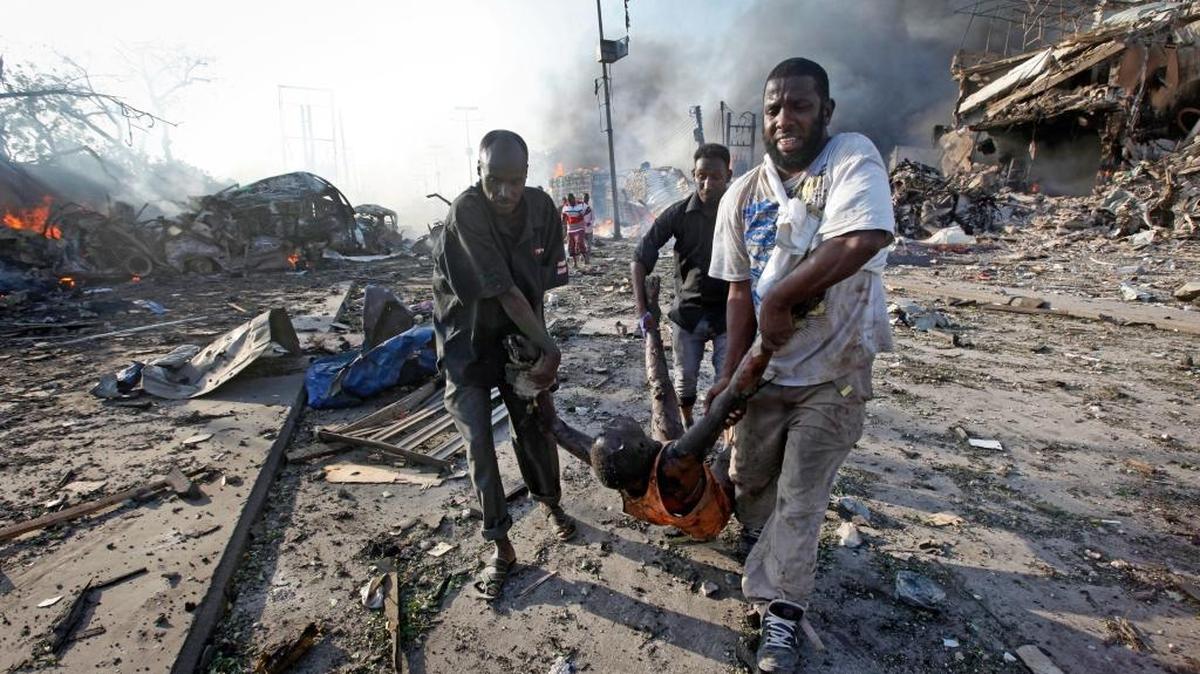 In this Oct. 14, 2017, file photo Somalis remove the body of a man killed in a blast in the capital Mogadishu, Somalia. A huge explosion from a truck bomb killed at least 20 people in Somalia’s capital, police said, as shaken residents called it the most powerful blast they’d heard in years.