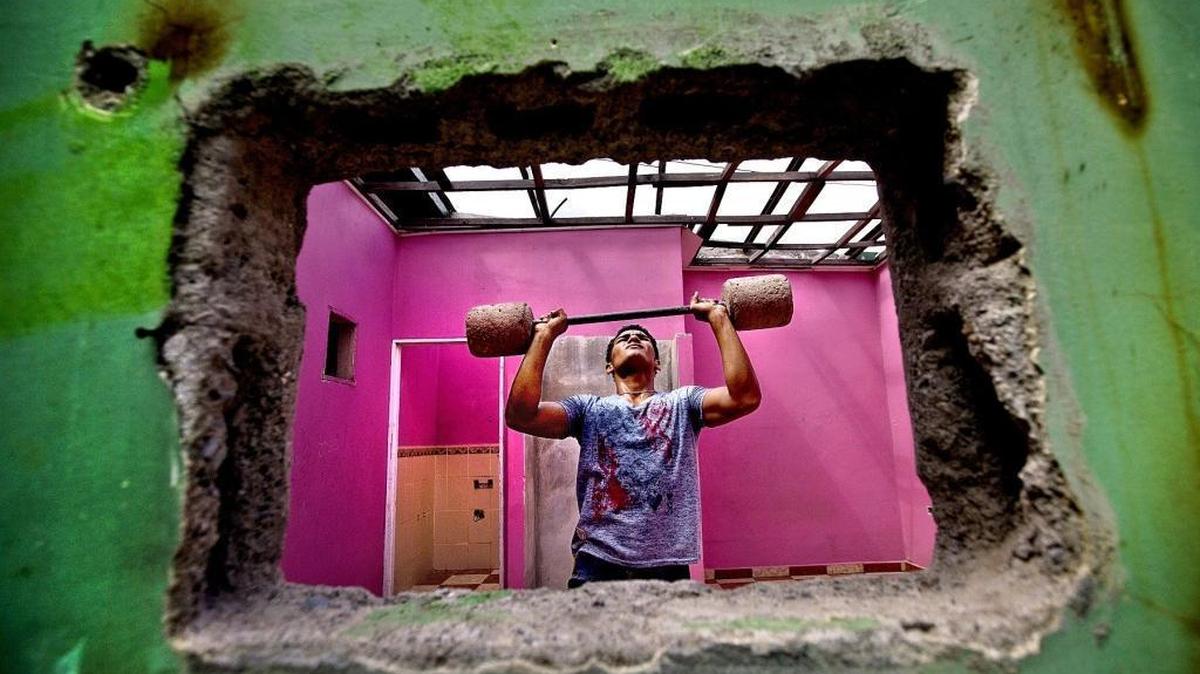 
Kevin Portillo, 17, works out with a homemade barbell in a space that will eventually be a gym. The space was formerly a casa loca or madhouse, one of many criminal lairs in Honduras. In this part of San Pedro Sula,  police reform and security are key to improving life in a violent nation.
