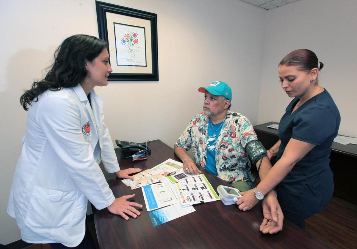 Dr. Michelle Weiner talks with a patient about medical marijuana as medical assistant Gina Santiago takes his blood pressure in 2017 in Miami.