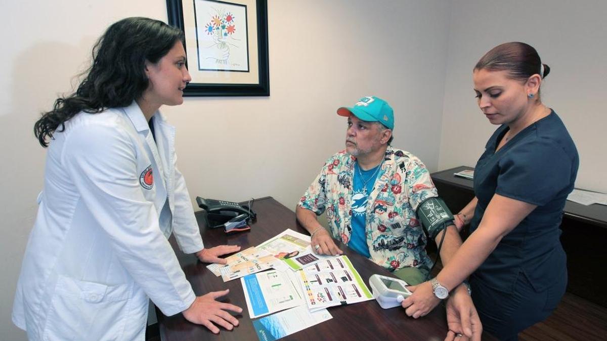 Dr. Michelle Weiner talks with patient Charles Quinones as medical assistant Gina Santiago takes his blood pressure.