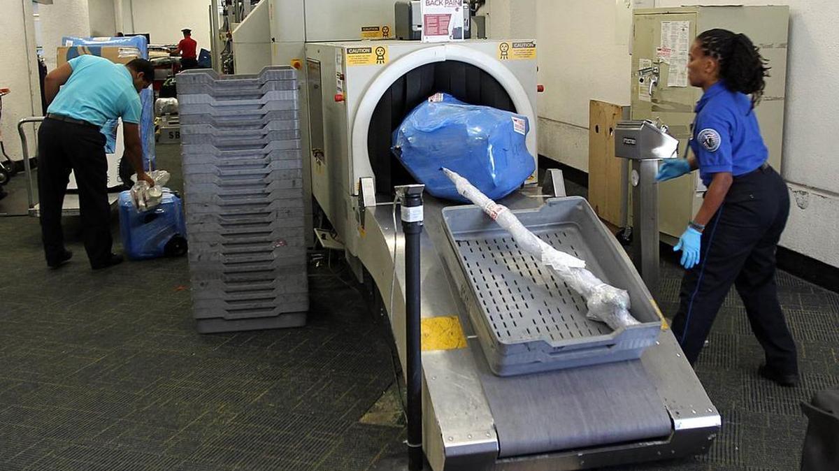 TSA personnel work security equipment at Miami International Airport.
