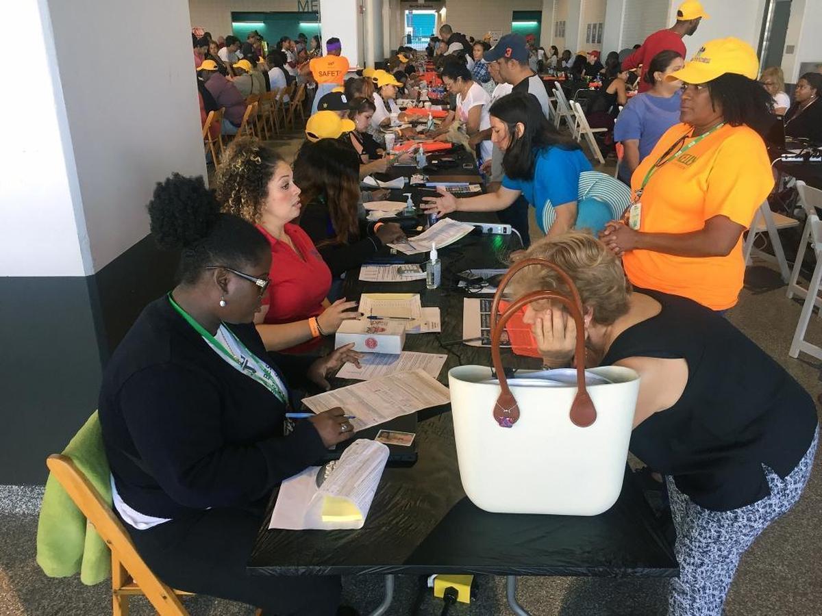 Workers help fill out paperwork for applicants as thousands are lined up early Thursday, Nov. 9, 2017, at Hard Rock Stadium in Miami Gardens to register for emergency food assistance.